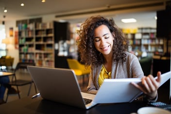 Young afro american woman sitting at table with books and laptop for finding information